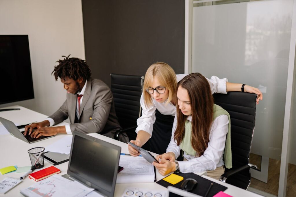 Business team collaborating in a modern office setting with laptops and tablets.